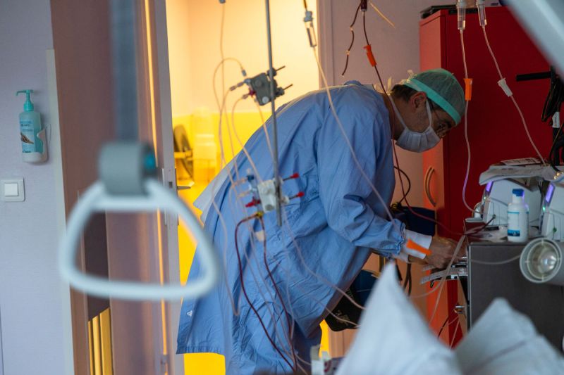 Un soignant en blouse penché sur un malade - crédit photo David Cesbron