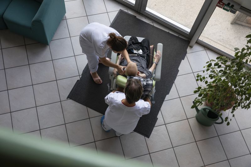 Deux infirmères affairées auprès d'une personne en fauteuil, vu du dessus. Crédit photo : David Cesbron